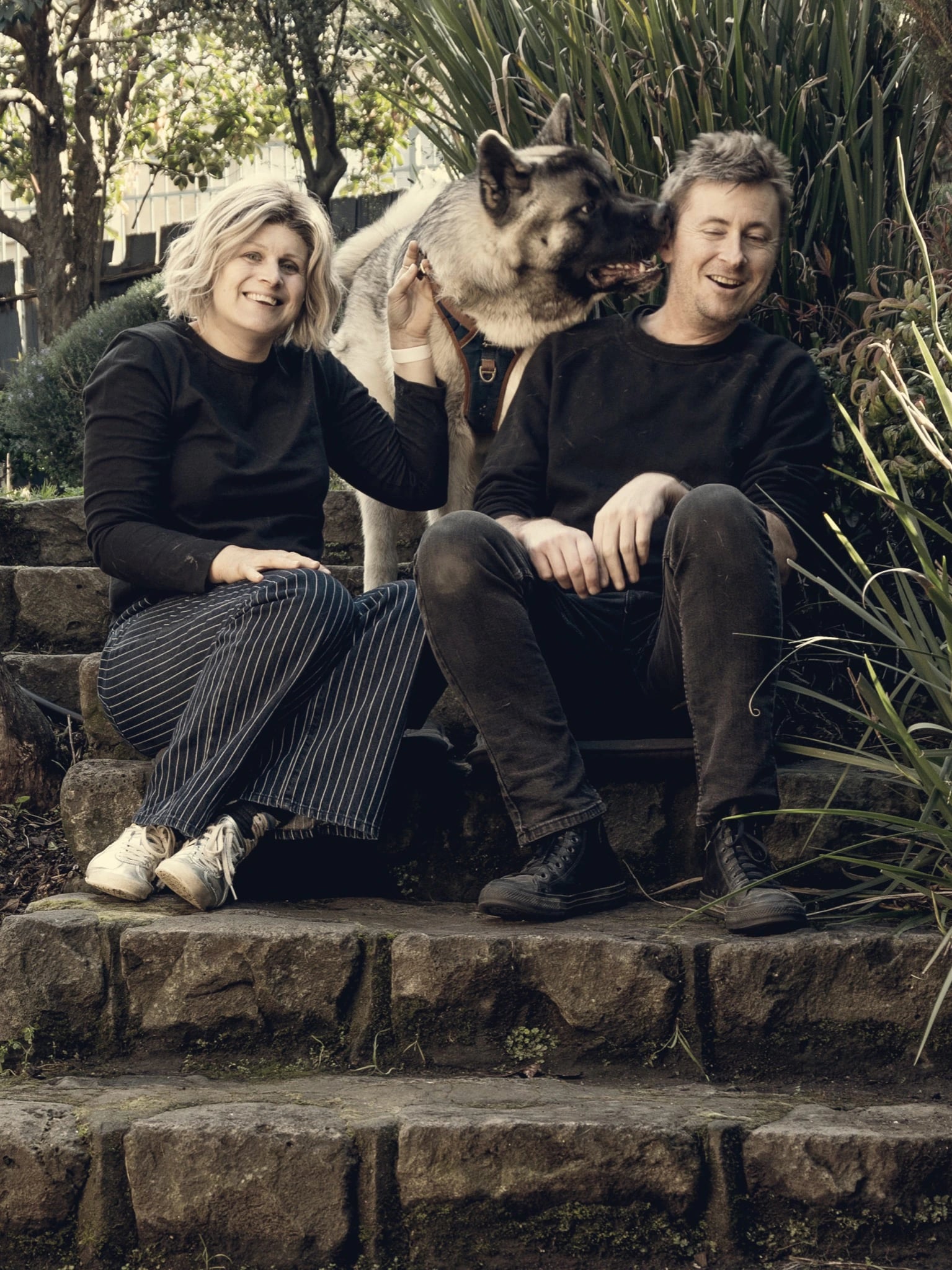 The two of us sitting on the stone steps of a garden in Melbourne, both in black and laughing in the winter sun, with our grey-and-white dog standing between us and nosing into one of our ears.