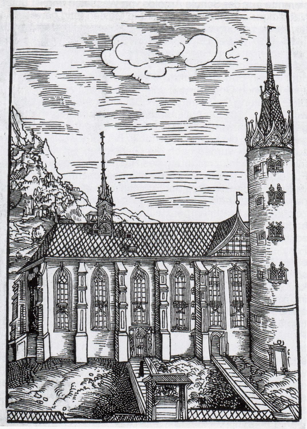 A woodcut of a tall Gothic church seen from outside: stepped buttresses, tall pointed windows with stone tracery, a steep roof of diamond-patterned tiles, a small spired turret on the ridge, and a massive round tower with a crowned spire rising at the right. Two doors in the long wall are reached by plank ramps up a grassy bank, and a paling fence encloses the ground.