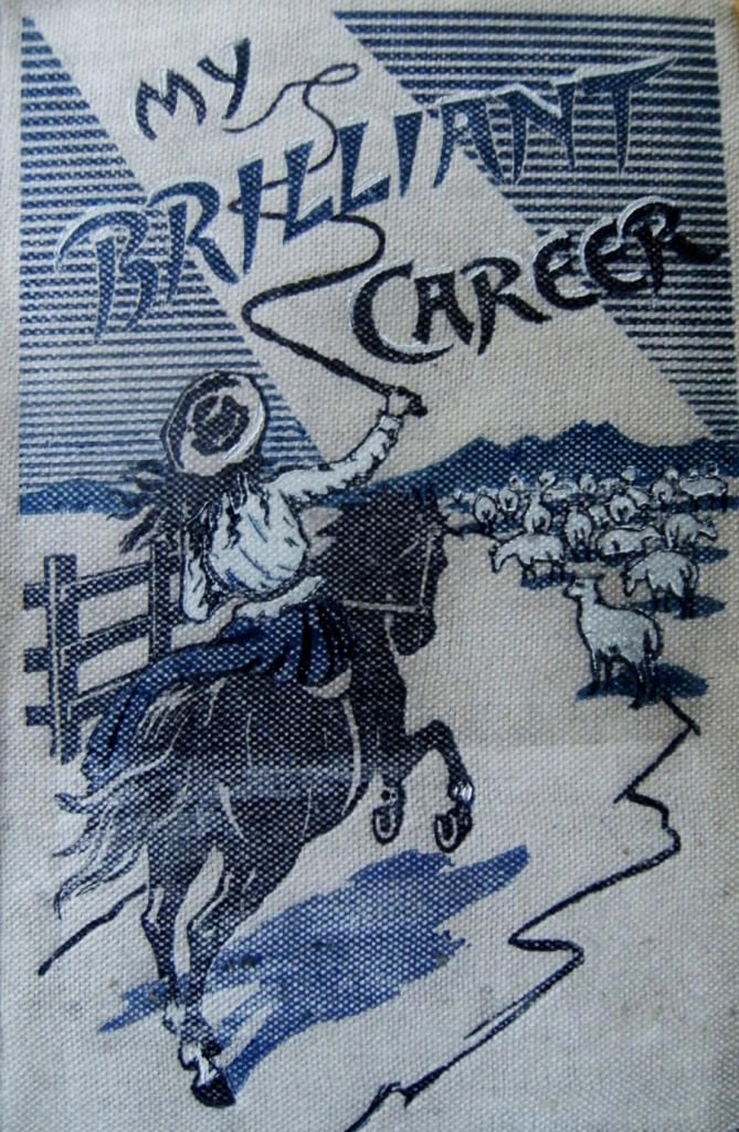 The front board of a book bound in pale cream cloth printed in dark blue-black ink. A drawn title reads My Brilliant Career across the top in ornate lettering, with the author's name below it, over an illustration of a woman in a wide hat on horseback raising a stockwhip and driving sheep past a post-and-rail fence.