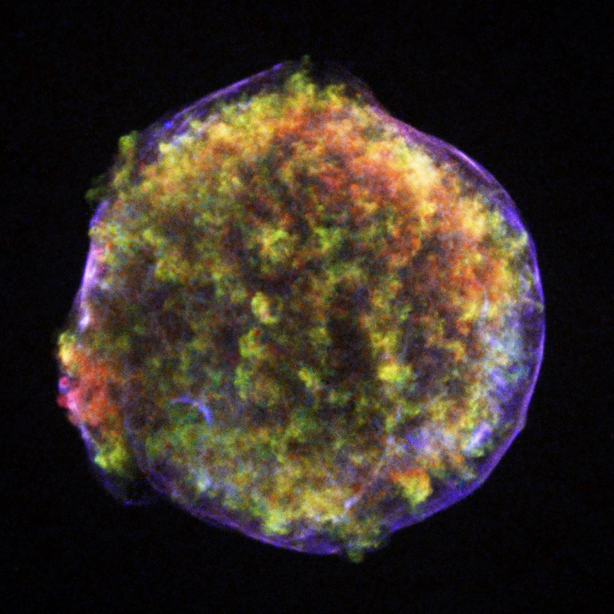 An X-ray image of a supernova remnant against black space: a nearly circular shell of mottled orange, yellow and green debris, wrapped in a thin outer rim of blue-violet light.